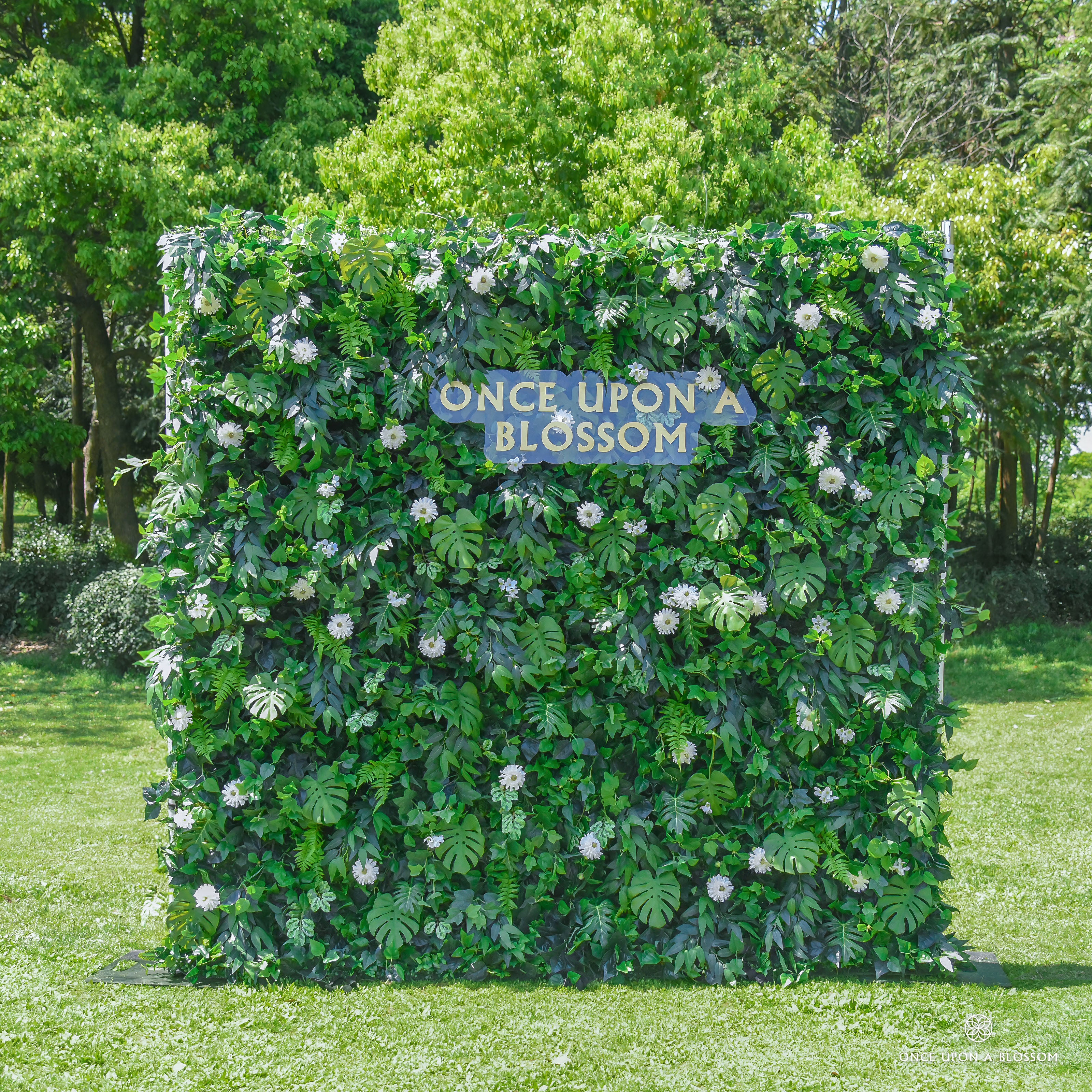 front view of greenery wall featuring chrysanthemums, pothos, and monstera leaves, from our Pearl Garden.