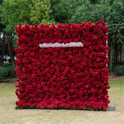 Flower wall of red roses with 'Once Upon a Blossom' branding in an outdoor setting, vibrant design for weddings