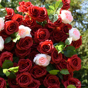 Close-up of deep red silk roses with soft pink and white roses and green leaves on the Date Night flower wall