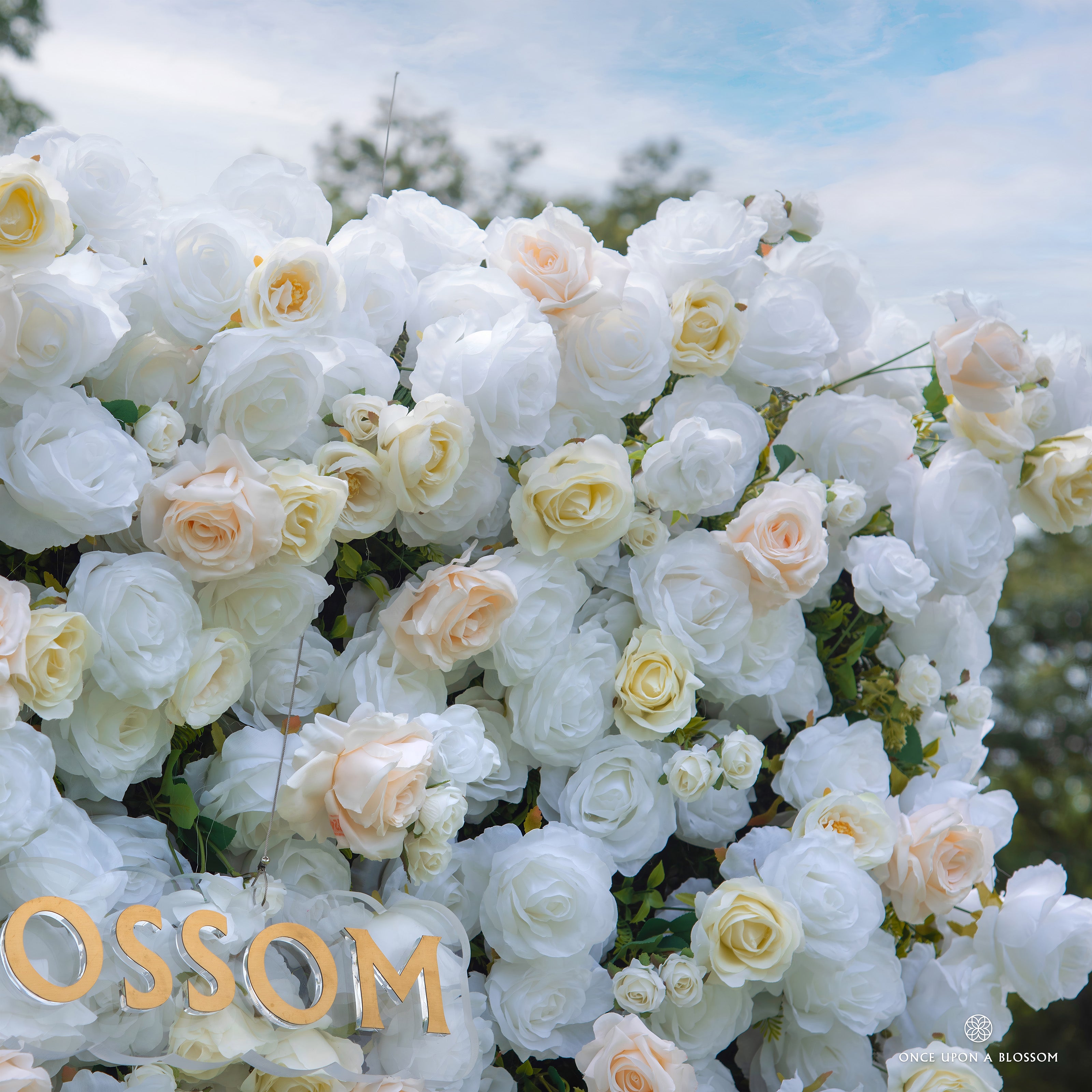 Soft white and peach flowers featured on Ever After bridal shower backdrop