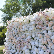 Angled view along the top of the First Blush white flower wall, with blush roses scattered through white blooms