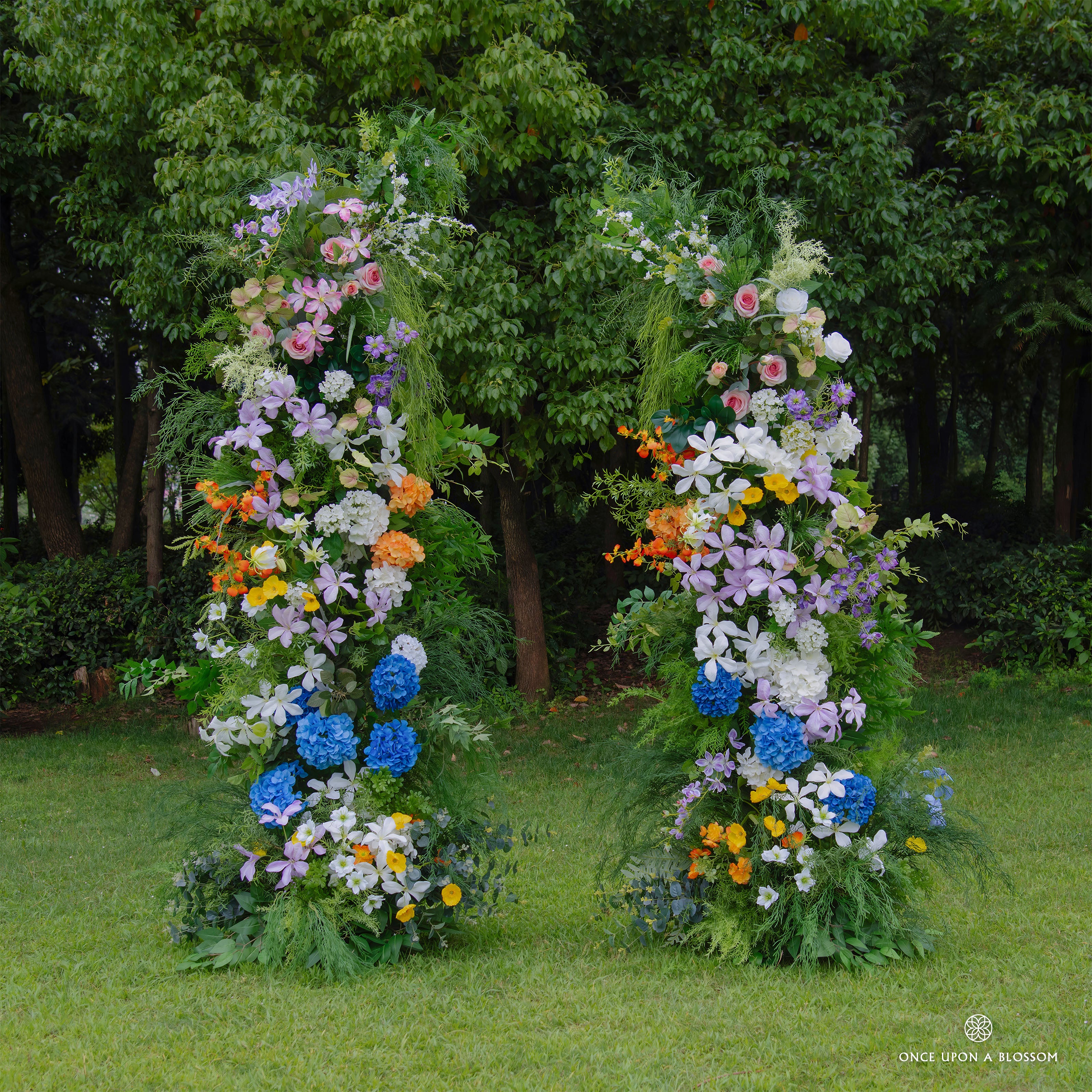 Front view of Wild Pop flower arch with vibrant blue, pink, yellow, and purple blooms.