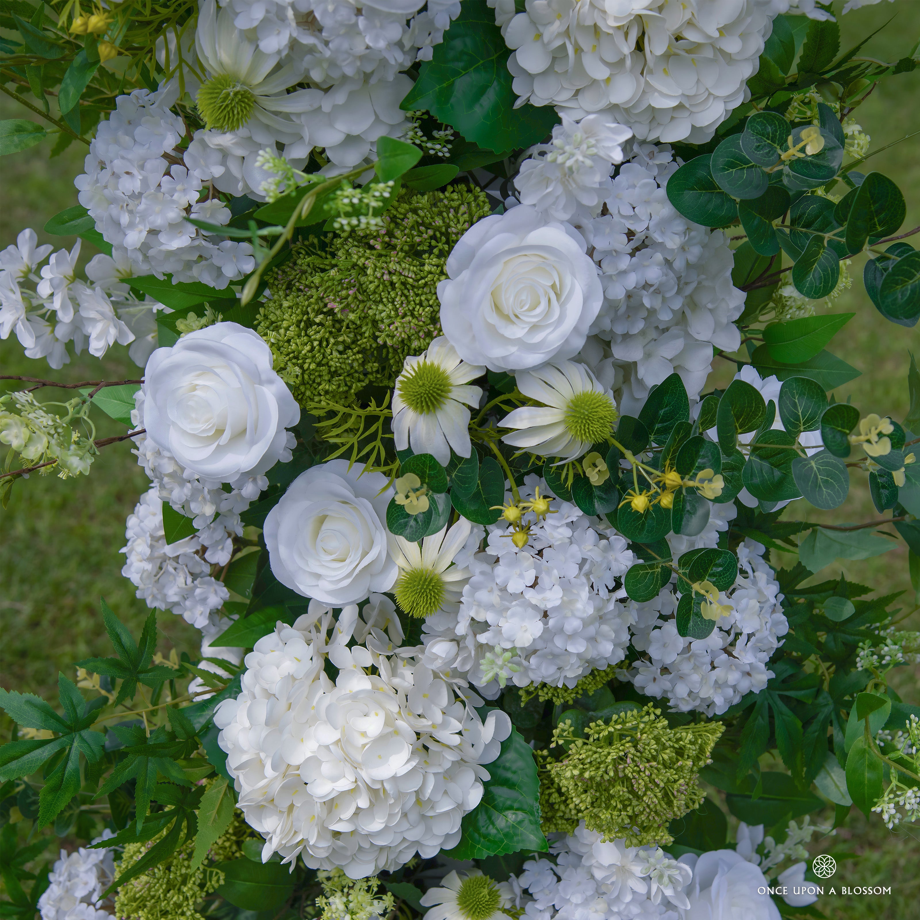 Detailed view of Be Here Now flower arch—greenery and white floral arrangement.