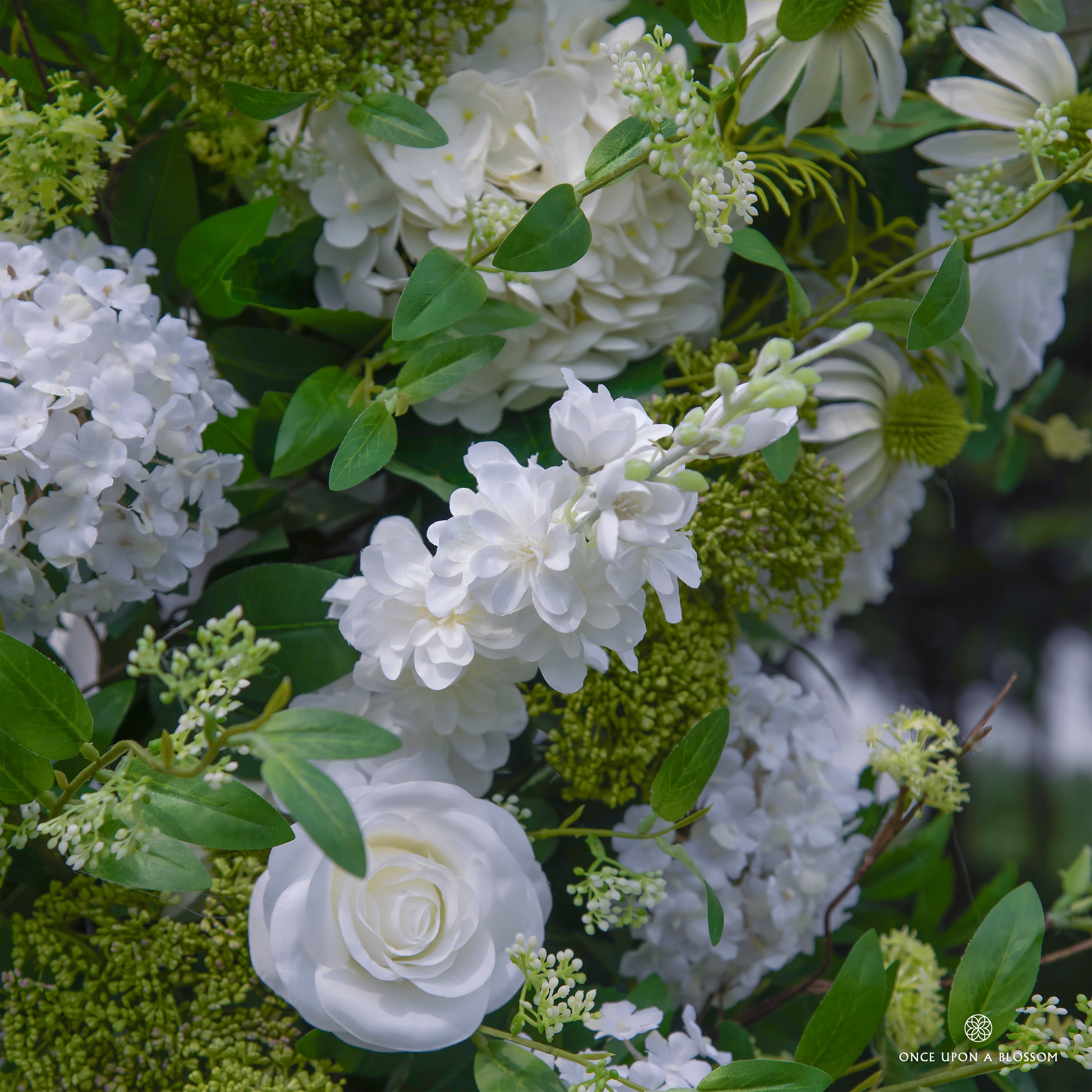 Detailed view of Be Here Now flower arch—greenery and white floral arrangement.