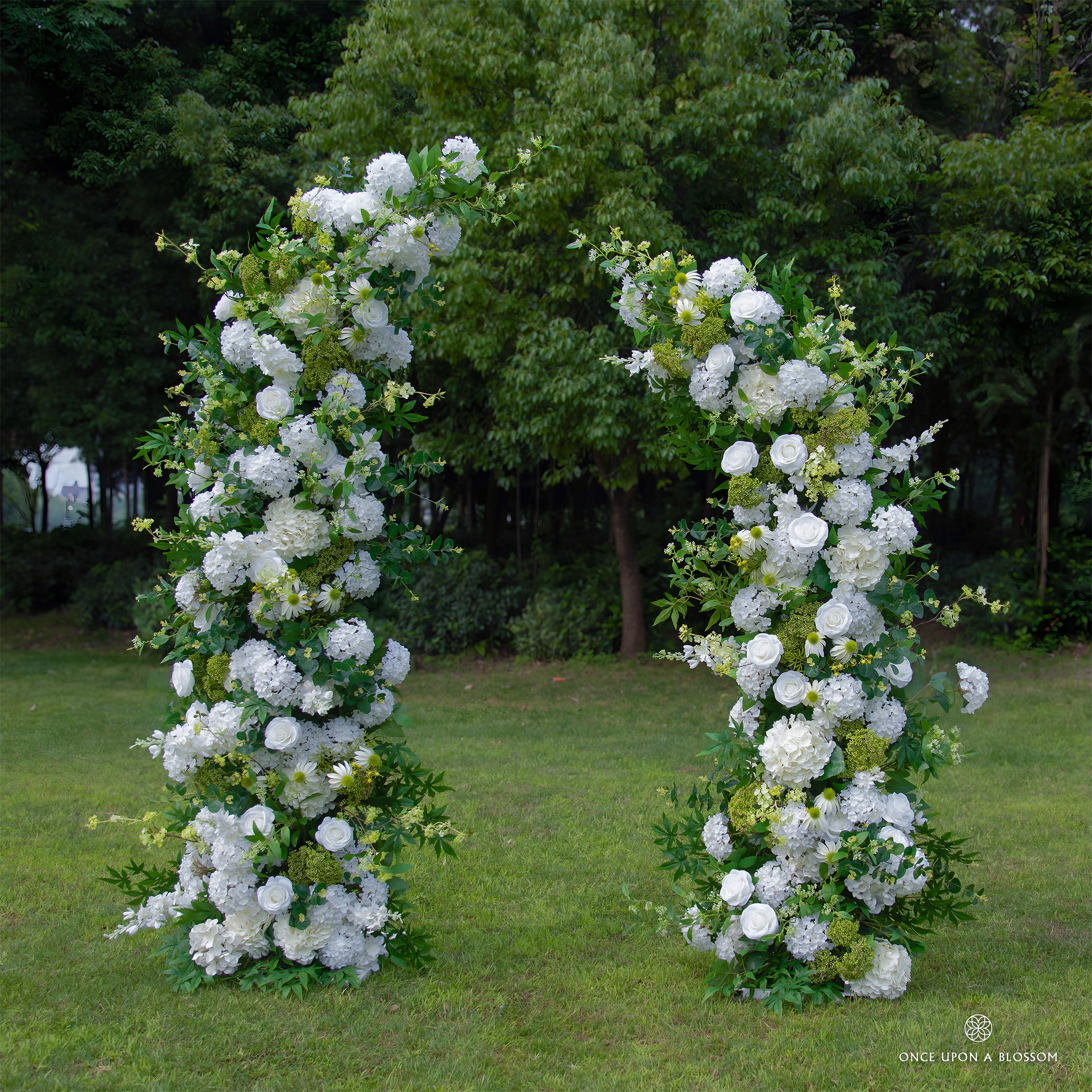 Front view of Be Here Now white flower arch with roses, hydrangeas, and greenery.