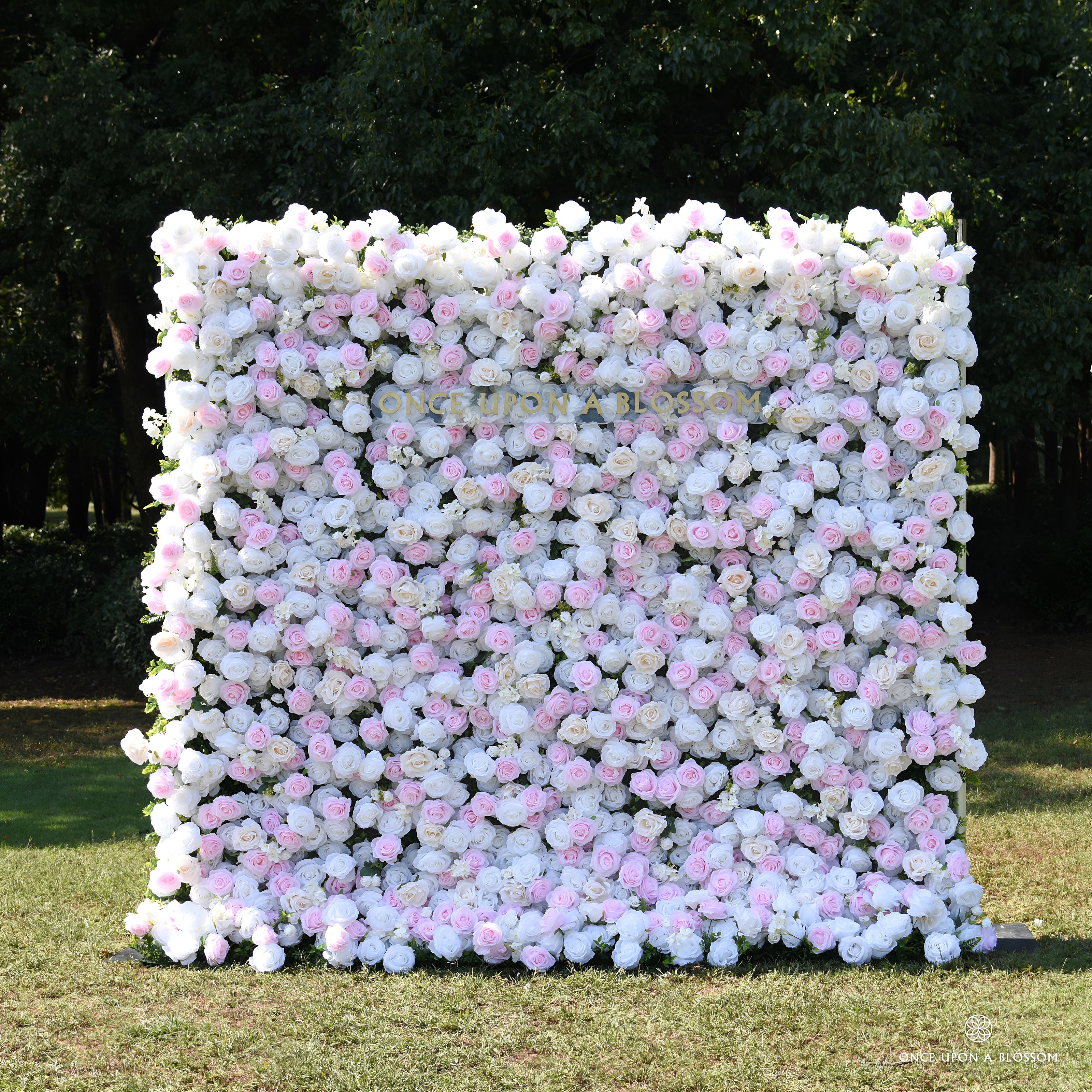 Front view of the Sweet Nothings pink and white flower wall backdrop, set outdoors for bridal showers and weddings